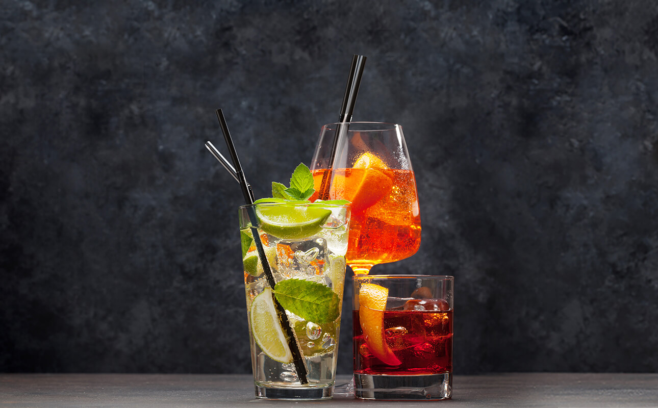 Drei fruchtige Cocktails mit grauer Wand im Hintergrund.