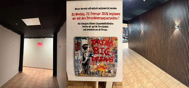 Baustelle im Gang zur Toilette. Hinweisschild. Wand mit Holzpaneelen.